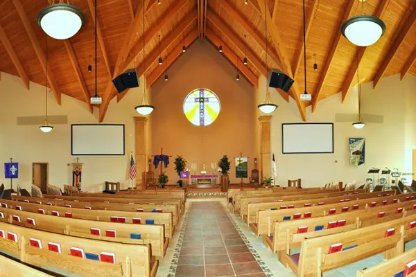 A church with pews and a large cross on the wall.