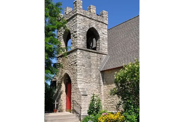 A stone church with a bell tower and red door.